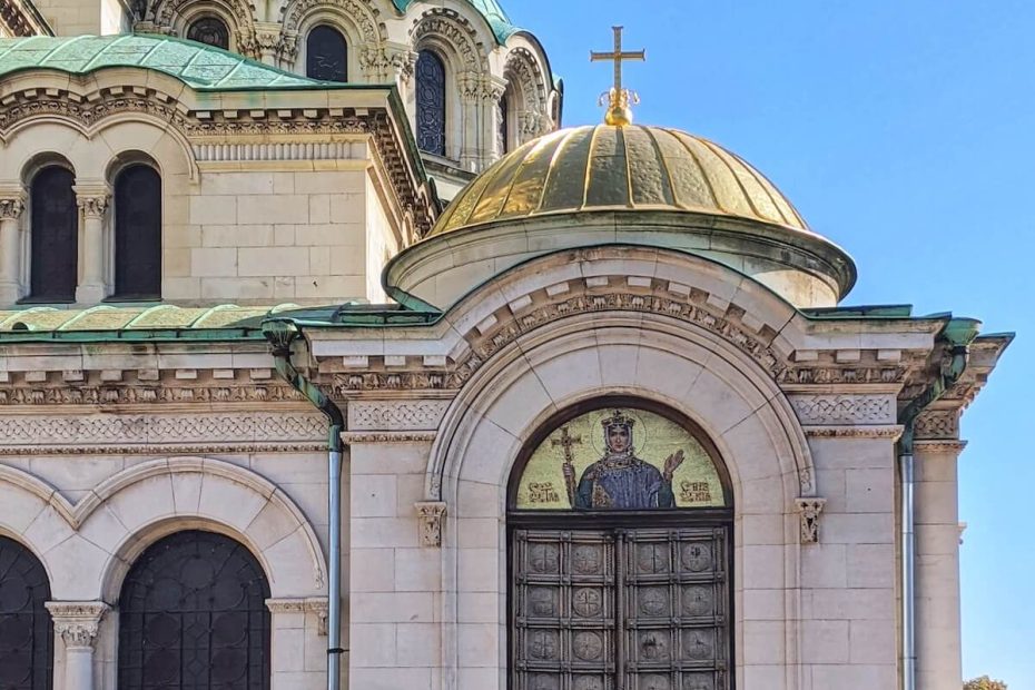 Wooden door with ornate carved panels. The transom features a saint in gold leaf. The door is attached to a church in Sofia Bulgaria.